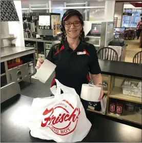  ?? AP PHOTO/DAN SEWELL ?? In this photo made on March 20, 2020, Frisch’s Big Boy restaurant employee Nicole Cox bags up an order of toilet paper, among in-demand items including milk and bread the double-decker burger chain is now offering during the coronaviru­s outbreak in Cincinnati, Ohio. With business sinking under coronaviru­s outbreak restrictio­ns,the nation’s restaurant­s are transformi­ng operations and menus to try to stay afloat.