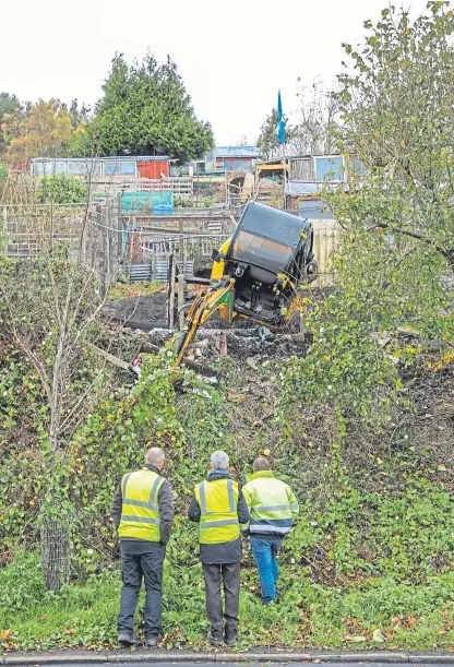  ?? Picture: Steven Brown. ?? Council workers attempt to right a digger after it toppled over during work.