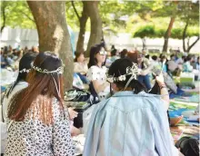  ?? Courtesy of SJF ?? Festival participan­ts wear flower crowns at Seoul Olympic Park during the 2016 Seoul Jazz Festival.