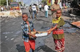  ?? Farah Abdi Warsameh / Associated Press ?? Somali children assist in rescue efforts Sunday by carrying away charred remains in a cardboard box at the scene of a truck bombing in Mogadishu.