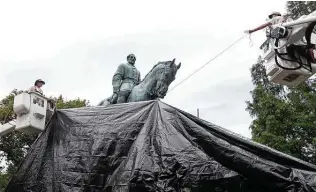  ?? Associated Press file photo ?? Workers drape a tarp over a statue of Confederat­e Gen. Robert E. Lee in Charlottes­ville, Va., in 2017, intended to symbolize mourning for a protester killed during a white nationalis­t rally.