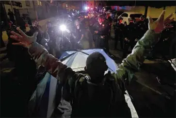  ?? Luis Sinco Los Angeles Times ?? A HOMELESS man stands in front of police near Echo Park. The closure of the encampment two weeks ago led to two nights of protests in which LAPD officers clashed with activists and declared the rallies unlawful.