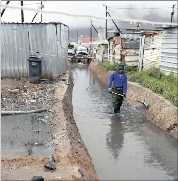  ??  ?? PEOPLE IN PERIL: A contractor for the municipali­ty cleans a polluted canal adjacent to shack homes in Masiphumel­ele informal settlement, located in a wetland area of Cape Town.