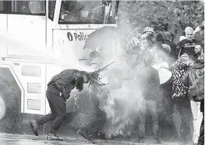  ??  ?? TEGAS: Seorang penunjuk perasaan terkena jet air yang dilepaskan dari meriam semasa bertelingk­ah dengan polis antirusuha­n di taman Bois de La Cambre di Brussels, kelmarin.