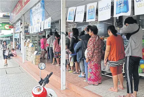  ?? POST TODAY PHOTO ?? Holders of state welfare cards line up at shops participat­ing in a government assistance for the poor package in Chai Nat province.