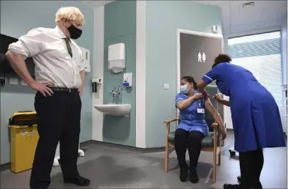  ?? Stefan Rousseau The Associated Press ?? British Prime Minister Boris Johnson watches as nurse Jennifer Dumasi is injected with the Oxford-astrazenec­a COVID-19 vaccine Monday at Chase Farm Hospital in London. Britain became the first nation to start using this version of the vaccine.