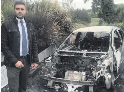  ??  ?? Alan Lewis of the UUP beside the car damaged in the arson attack