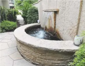  ??  ?? A path of irregular slabs of stone contrast in shape and texture with the materials used to construct a formal fountain in a Washington Park home.