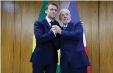  ?? — AFP photo ?? Lula (right) and Macron pose for a picture during a bilateral agreement signing ceremony at the Planalto Palace in Brasilia.