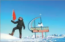  ??  ?? Wu Yu holds the Chinese flag aloft after reaching Yuryung-khaya, the most northerly village inside the Arctic Circle.