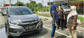  ?? GALIH ADI/JAWA POS ?? PENGAWASAN KETAT: Petugas mengecek suhu tubuh pendatang yang hendak masuk Surabaya di pos penjagaan Gunung Anyar kemarin. Pelanggara­n mudik dan tidak bermasker sering ditemukan.