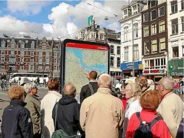  ??  ?? Help is close at hand: Having a tour guide means not getting lost. Here, the tour leader is pointing out to the group where they are exactly in amsterdam’s maze of streets.