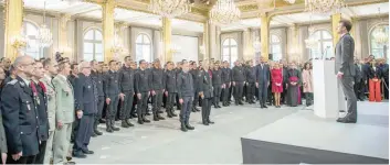  ?? — AFP ?? President Emmanuel Macron (R) and the audience stand guard at the Elysee presidenti­al Palace in Paris on Thursday, during a tribute ceremony to fire brigade staff and other emergency workers who saved Notre-dame de Paris Cathedrale in the devastatin­g blaze three days ago.