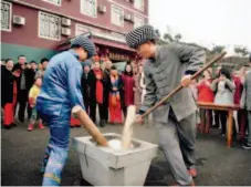  ??  ?? January 31, 2018: Two men perform with Ciba, glutinous rice cake, in Songtao Miao Autonomous County in Tongren City, southweste­rn China’s Guizhou Province. Folk customs in the countrysid­e are attractive to tourists. VCG