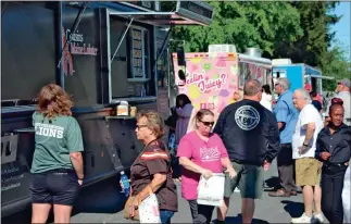  ?? Jeremy Stewart ?? People line up and get food at some of the food trucks that were part of the Moms United food truck festival in downtown Cedartown on Saturday, April 22. The event helped the nonprofit raise money to help mothers dealing with sudden unexpected infant death and other issues.