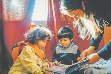  ?? JAMIE KELTER DAVIS/NEW YORK TIMES ?? Alejandra Martinez reads with two of her three sons Thursday in their Chicago apartment. Most public schools in Chicago were closed for a third day Friday.