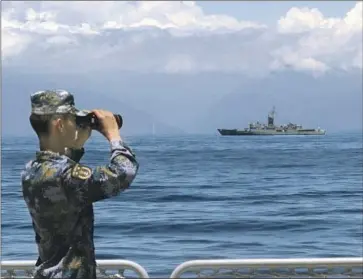  ?? Lin Jian Xinhua ?? A MEMBER of the People’s Liberation Army takes part in China’s military exercises, with the Taiwanese frigate Lan Yang in the background. The nearly weeklong maneuvers near Taiwan appear to be winding down.