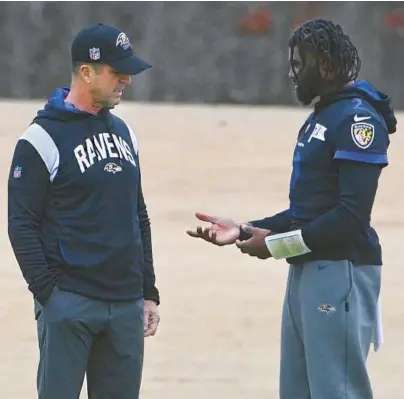  ?? KEVIN RICHARDSON/BALTIMORE SUN ?? Ravens quarterbac­k Tyler Huntley, right, talks with coach John Harbaugh during practice on Wednesday. Huntley was limited on Thursday as he deals with injuries to his right wrist and right throwing shoulder.