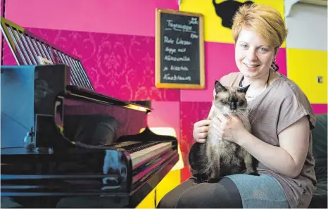  ?? FOTO: DPA ?? Café-Besitzerin Caroline Braune mit Kater Jackey-Smokey: Zum Konzept von „Zur Mieze“gehört auch die Verbindung mit Musik. Einmal pro Woche spielt ein Pianist ein klassische­s Konzert.