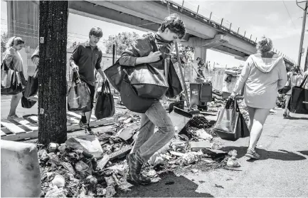  ?? Santiago Mejia / The Chronicle ?? HELPING HANDS: Below, Will Watson (center) and his friends from Brookwood Baptist Church in Alabama walk over debris that was charred in a recent fire to deliver essential supplies to people living in an encampment near Fifth and Brush streets.