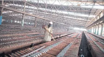  ?? SIMON DAWSON/BLOOMBERG ?? A worker handles copper sheets at Katanga Mining's copper and cobalt metallurgi­cal plant in Congo.