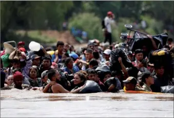  ?? CARLOS GARCIA RAWLINS / REUTERS ?? Central American migrants wade through the Suchiate River, the natural border between Guatemala and Mexico, on Monday in their bid to reach the United States.