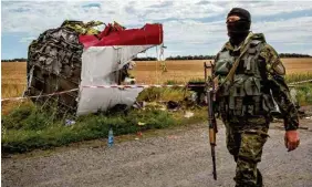  ?? MAURICIO LIMA/THE NEW YORK TIMES FILE PHOTO ?? A pro-Russian militiaman walks past part of the aircraft at the crash site of Malaysian Airlines Flight 17 near Grabovo, Ukraine, on July 20, 2014.