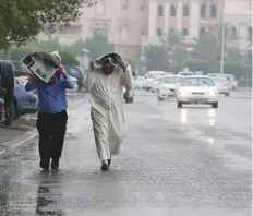  ?? AFP ?? Residents shield themselves from the downpour in Kuwait City on Wednesday.