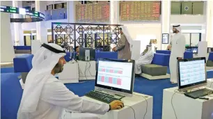  ?? — Reuters ?? Investors check stock market activity at the Dubai Internatio­nal Financial Market.
