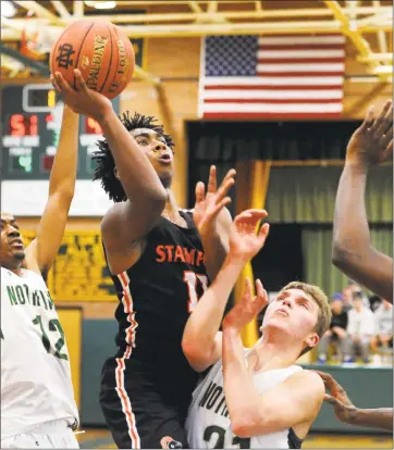  ?? Christian Abraham / Hearst Connecticu­t Media ?? Stamford’s Jay Jaudon (11) attempts a shot as Notre Dame-West Haven’s Zach Laput (21) defends during the Winter Snow Jam Christmas tournament final in West Haven on Saturday.