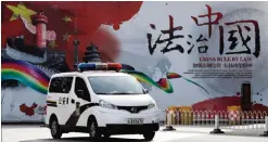  ??  ?? BEIJING: A police car drives past a Chinese government’s propaganda billboard reading “China Rule By Law” on a street.