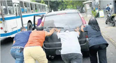  ?? AP ?? People push a car that ran out of gas to a state-run oil company PDVSA filling station in Caracas, Venezuela, yesterday. The first of five tankers loaded with gasolene sent from Iran this week is expected to temporaril­y ease Venezuela’s fuel crunch while defying Trump administra­tion sanctions targeting the two US foes.