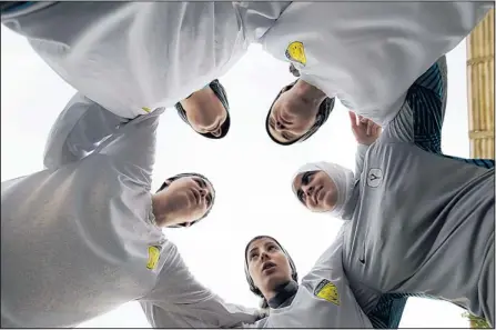  ?? HASSAN AMMAR/THE ASSOCIATED PRESS ?? Members of a Saudi female soccer team listen to their team captain, Rawh Abdullah, bottom center, before a training session in May. Some fear women athletes will be punished by hardline Muslim leaders for being pressured by the West.