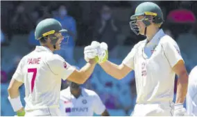  ??  ?? Australia’s Captain Tim Paine (left) congratula­tes his teammate Cameron Green on scoring a half-century (50 runs) on the fourth day of the third cricket Test match between Australia and India at the Cricket and Sports Ground in Sydney on Sunday.