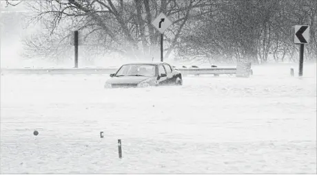  ?? MATHEW MCCARTHY WATERLOO REGION RECORD ?? A car was abandoned as the Nith River covered Hutchinson Road in Wellesley on Tuesday.