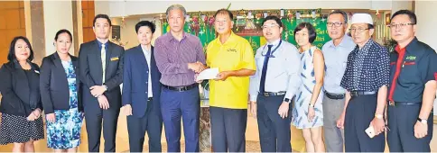  ??  ?? Ting (centre) receives the donation from Pui at Dynasty Hotel.