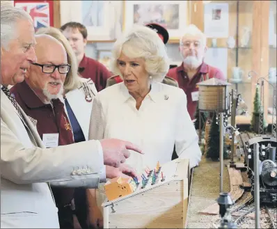  ??  ?? The Prince of Wales and the Duchess of Cornwall try out a model railway with hobbyists at Llandovery Railway Station.