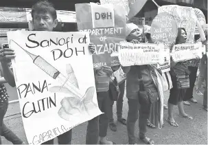  ?? — Gambar AFP ?? PROTES: Gambar 5 Disember menunjukka­n anggota dan penyokong kumpulan wanita GABRIELA membawa sepanduk dan melaungkan slogan di luar pejabat Jabatan Kesihatan di Manila ekoran penggantun­gan penjualan dan pengagihan vaksin antidenggi Sanofi, Dengvaxia.
