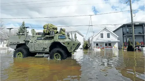  ?? SEAN KILPATRICK/THE CANADIAN PRESS ?? The military drives along a flooded street as waters breach the Gatineau River and flood the neighbourh­ood in Gatineau, Quebe., on Wednesday.