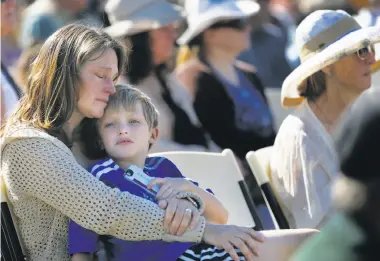  ?? Photos by Leah Millis / The Chronicle ?? Laura Schulze, above, holds her son Zachary, 8, during the Day of Remembranc­e at Santa Rosa Junior College, where hundreds of community members, officials and first responders gathered in Bailey Field, below.