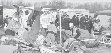  ??  ?? Agents dismantle shelters in the ‘jungle’ migrants and refugees camp in Calais, northern France. — AFP photo