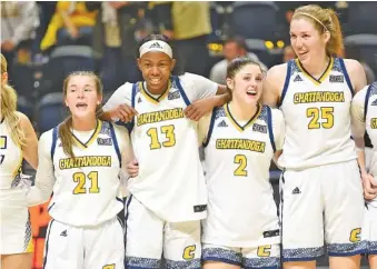  ?? STAFF PHOTO BY MATT HAMILTON ?? UTC players (21) Addie Grace Porter, (13) Yazz Wazeerud-Din, (2) Brooklyn Crouch and (25) Abbey Cornelius sway as they sing the school alma mater after defeating Mercer at McKenzie Arena on Jan. 14. UTC won 78-70 in overtime.