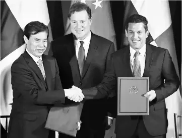  ??  ?? Chinese Minister of Commerce Zhong Shan (left) and Vice Foreign Minister of Panama Luis Miguel Hincapie (right) shake hands next to Panamamian President Juan Carlos Varela (center) at the Simon Bolivar Palace in Panama City on December 7. Zhong Shan is...