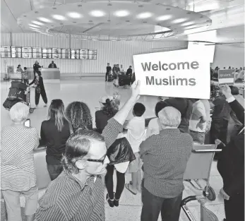  ?? MARK J. TERRILL, AP ?? John Wider holds up a sign welcoming Muslims at Los Angeles Internatio­nal Airport June 29.