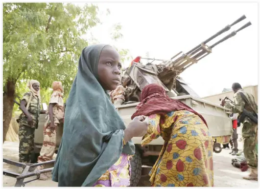  ??  ?? A girl stands in front of soldiers in the retaken town of Damasak, Nigeria, in this file photo. (Reuters)