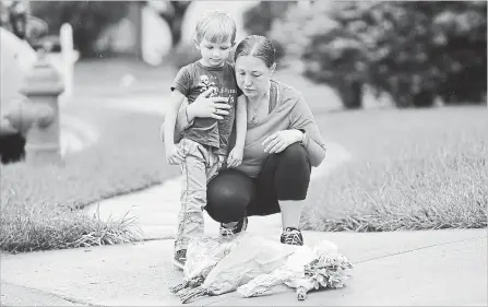  ?? LLOYD FOX
TNS ?? Christine Frey of Parkville with her son, David, 4, place flowers where Baltimore County Police Officer First Class Amy Caprio was killed.