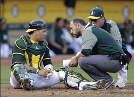  ?? BEN MARGOT — THE ASSOCIAGED PRESS ?? Oakland Athletics catcher Bruce Maxwell, left, is examined by trainer Nick Paparesta and manager Bob Melvin, right, after being hit on the head by a ball fouled by Tampa Bay Rays’ Brad Miller during the second inning of a baseball game Monday in Oakland.