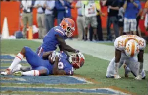  ?? JOHN RAOUX — THE ASSOCIATED PRESS ?? Florida wide receiver Tyrie Cleveland, bottom left, celebrates his game-winning touchdown with teammate Brandon Powell as Tennessee defensive back Micah Abernathy (22) hangs his head dejectedly as time expires Saturday in Gainesvill­e, Fla. Florida won...