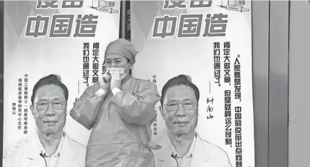  ?? NG HAN GUAN/AP ?? A medical worker adjusts her mask near propaganda boards showing Chinese medical expert Zhong Nanshan and the words “Vaccine China Made” outside a vaccinatio­n center in Beijing on Friday.
