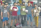  ?? VIPIN KUMAR/HT PHOTO ?? ■ Indian nationals deported from Mexico hold up their White Official Passports at the IGI Airport on Friday.